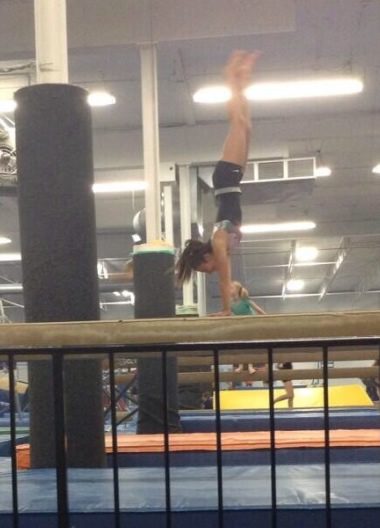 In the photo, Ashley Lorenco is doing a hand stand on a balance 