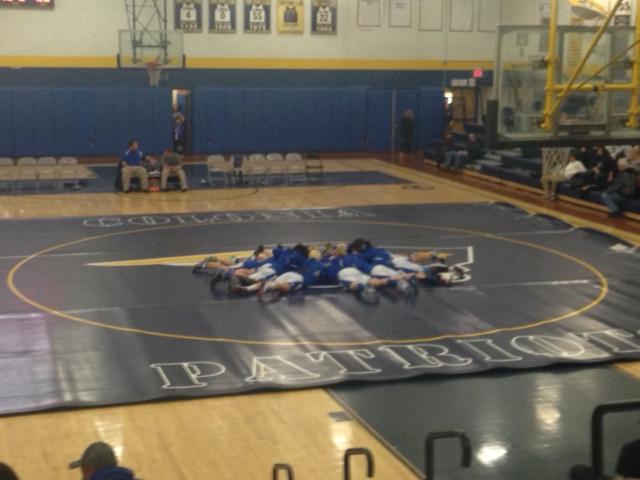 After warming up, the Sayreville team huddles up in the center of the mat before the start of the game.