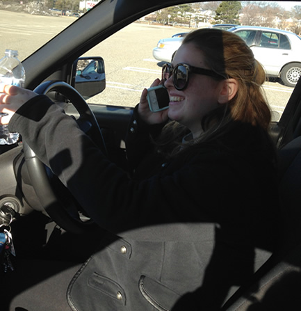 Student distracted at the wheel, texting, and drinking water while driving.