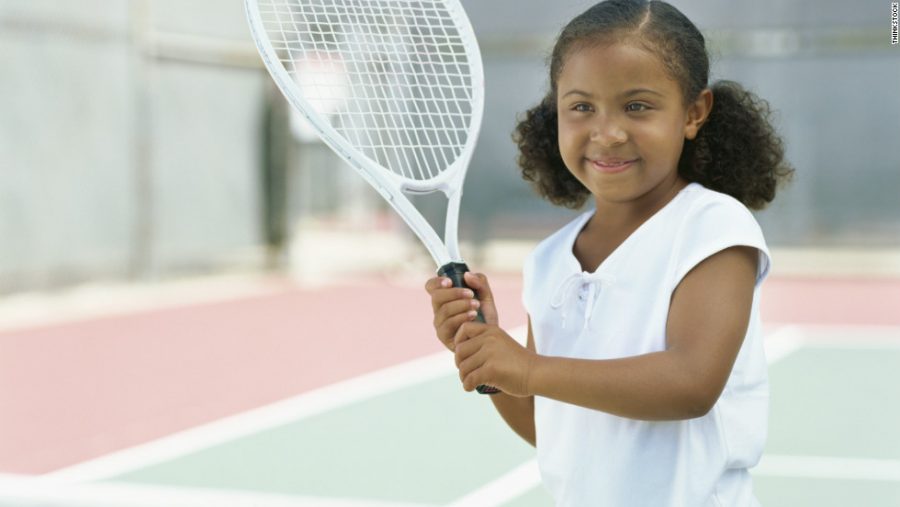 A young girl learning how to play tennis at a young age