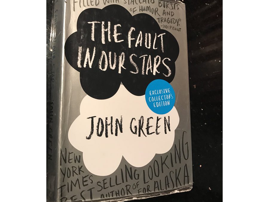 Displaying a worn and torn cover sleeve rests the exclusive collectors edition of The Fault in Our Stars.