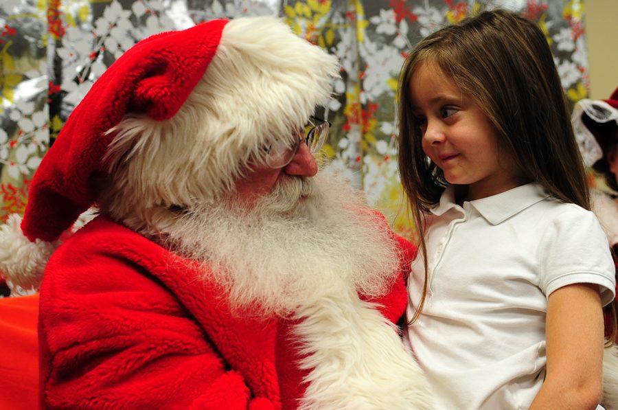 The obsequious Santa Claus listened carefully to what the little kid wanted for Christmas. 