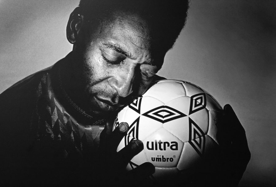Seen here is soccer legend Pele, holding a soccer ball close to his face.