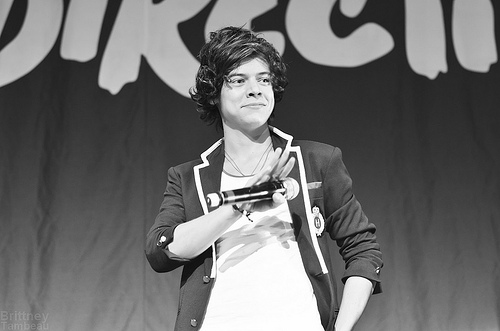 Waving to his fans, Harry Styles is about to perform with One Direction.