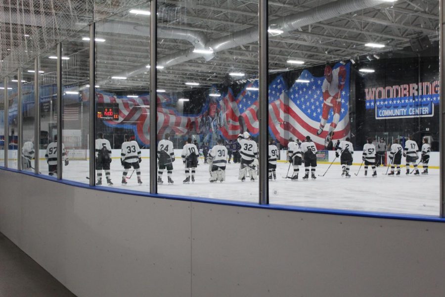 The hockey team lines up before their game starts, to listen to the National Anthem. 