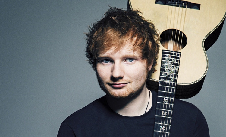 Holding his guitar, Ed Sheeran, makes history with his Divide album. 