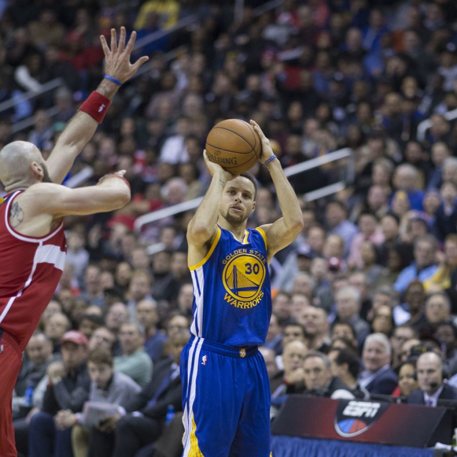 Seen here is NBA star Stephen Curry, shooting a three pointer over a Wizards defender.