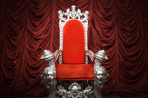 A costume prop chair in front of red drape.