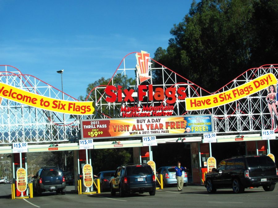 A group of people in the popular amusement park begin to enter via car as they pay for parking.