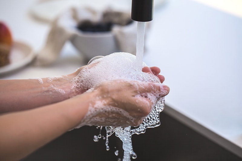 Soap bubbles gather in a pair of hands as they are washing in the kitchen.
