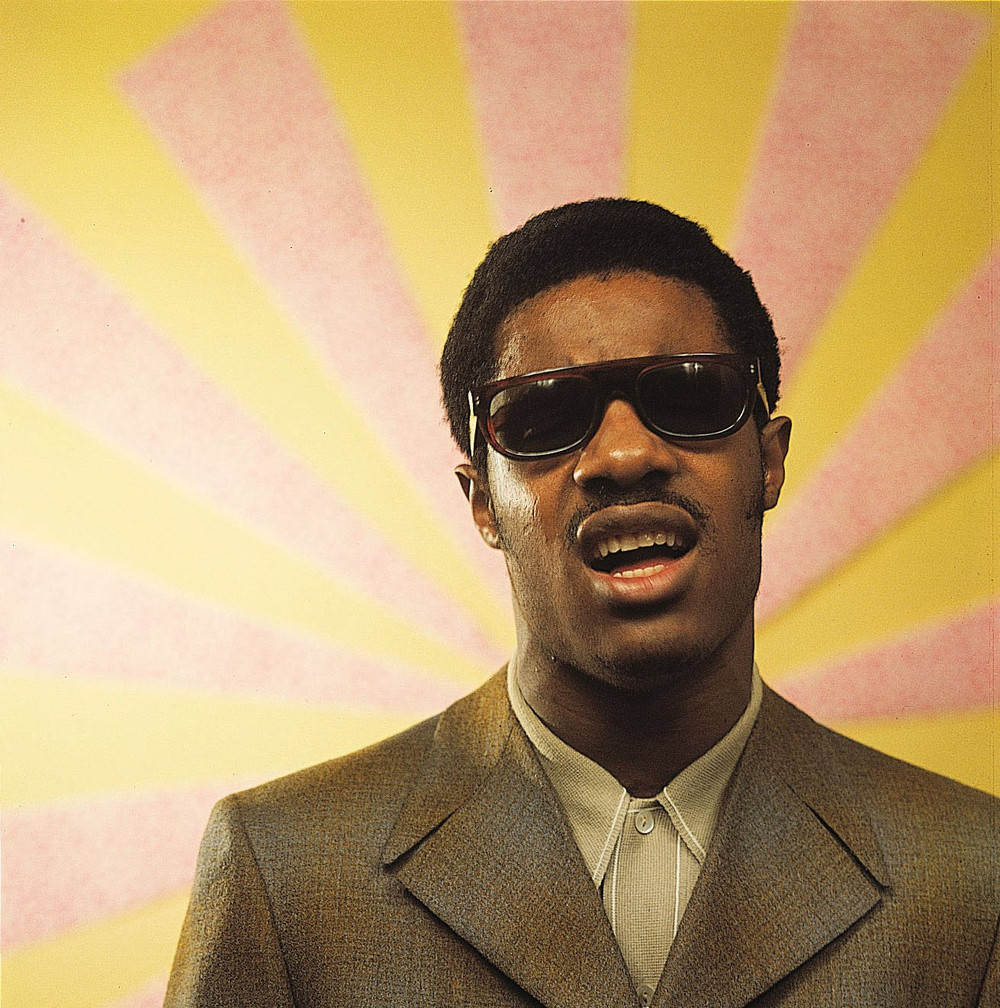Stevie Wonder posing In front of murals