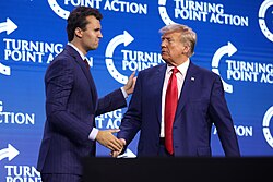 At a Turning Point USA Conference in 2023, social media personality Charlie Kirk and President Donald Trump are seen together. They were both associated with the group and speaking to attendees about the progrm. 
