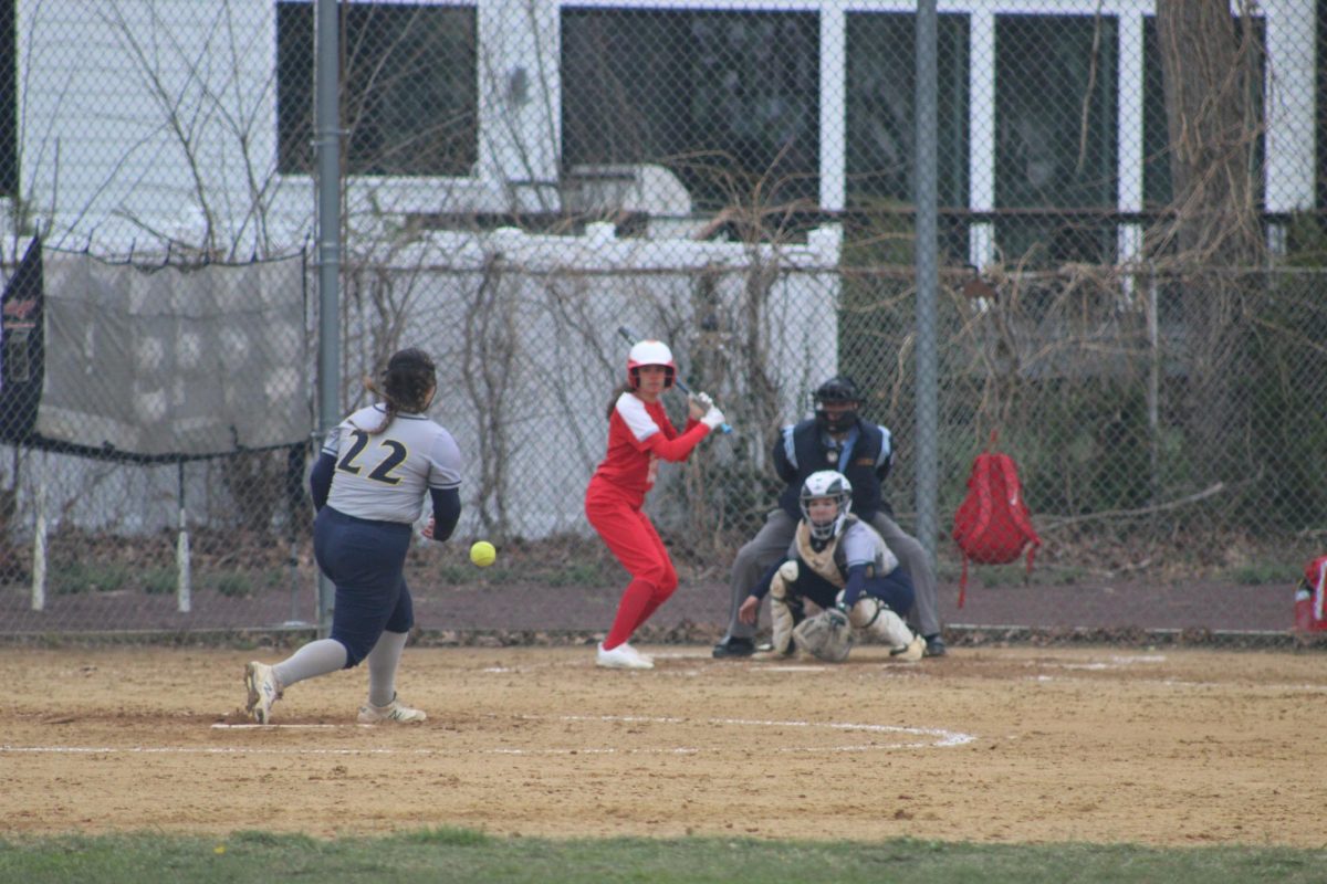  Colonia high school pitcher Megan throwing a strike against Edison high school on a cloudy day .