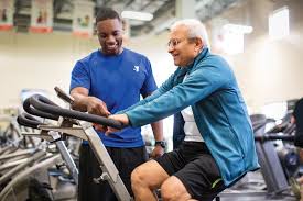 Elderly man exercising at YMCA with trainer. Less than 15% of U.S. adults aged 65 and older exercise. 